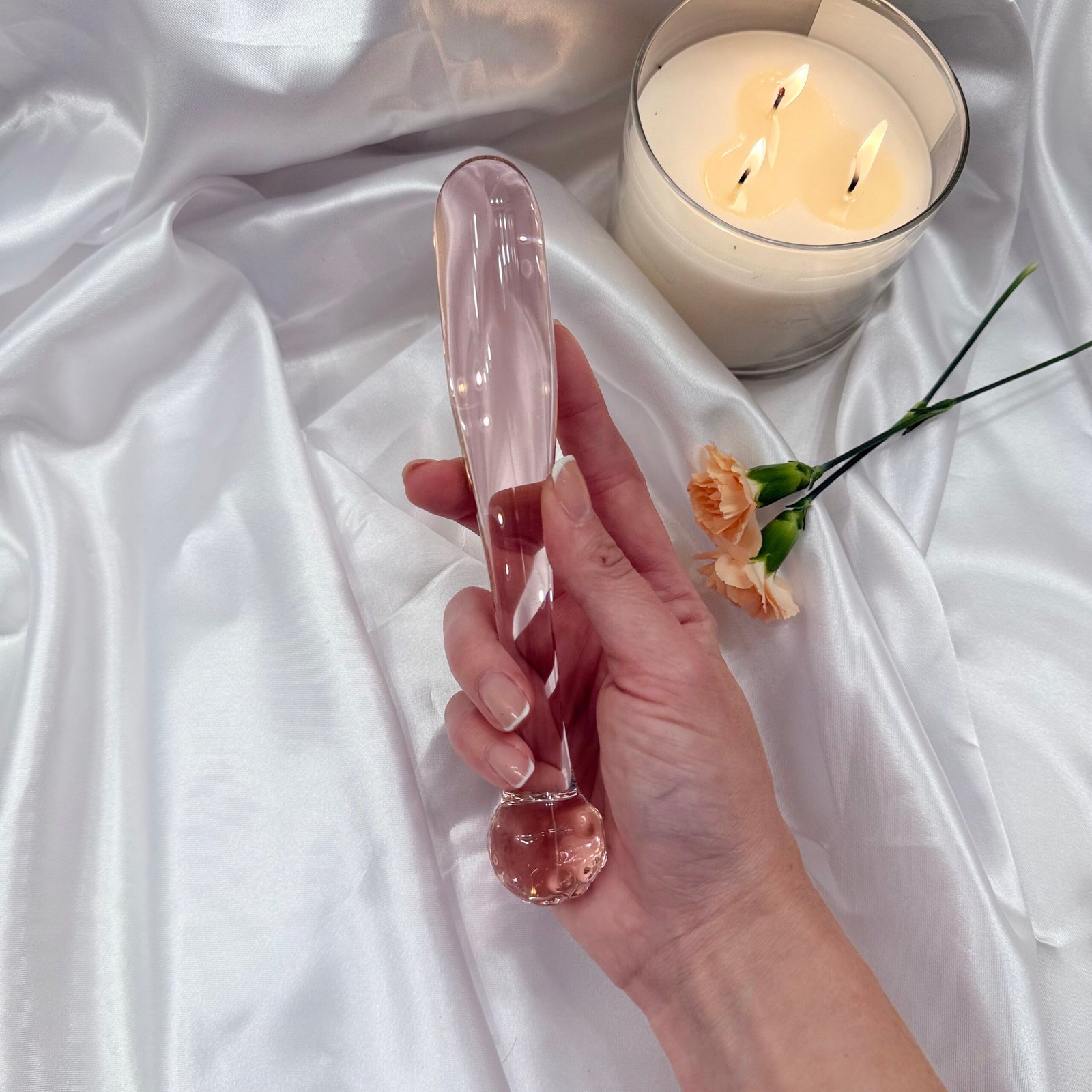 IMG_7438 Elegant rose quartz style glass dildo placed on satin fabric with candle in the background